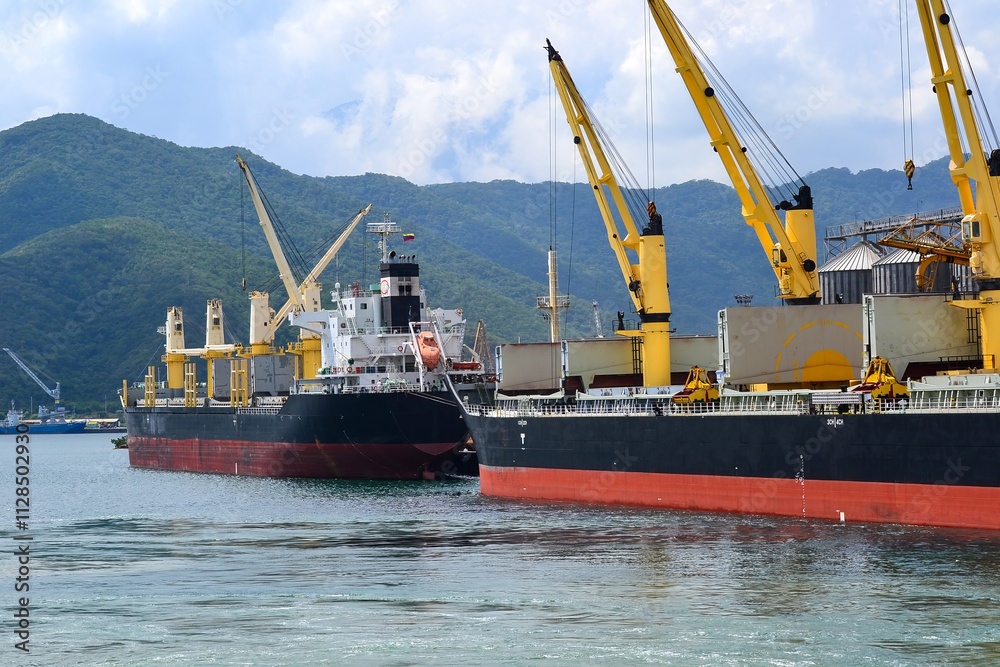 Fototapeta premium Bustling Port with Cargo Ships and Yellow Cranes in Coastal Setting