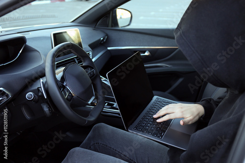 Tablou pe pânză Thief hacking car system with laptop inside vehicle, closeup
