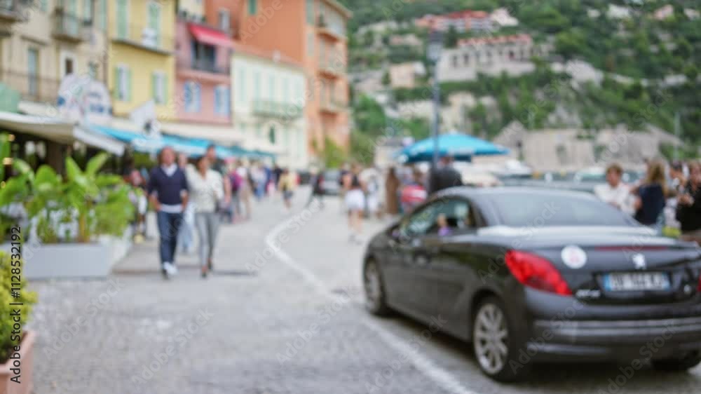 Blurred street scene in villefranche-sur-mer with people walking, dining outdoors by colorful buildings under a clear sky capturing vibrant city life with a defocused, bokeh effect. Blurred street scene in villefranche-sur-mer with people walking, dining outdoors by colorful buildings under a clear sky capturing vibrant city life with a defocused, bokeh effect.