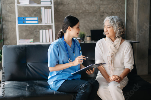 Asian caregiver doctor examine older patient woman therapist nurse at nursing home taking care of senior elderly woman sit on sofa photo