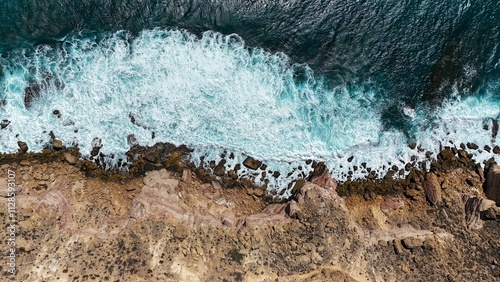 Aerial view of rocky coastline with crashing waves.