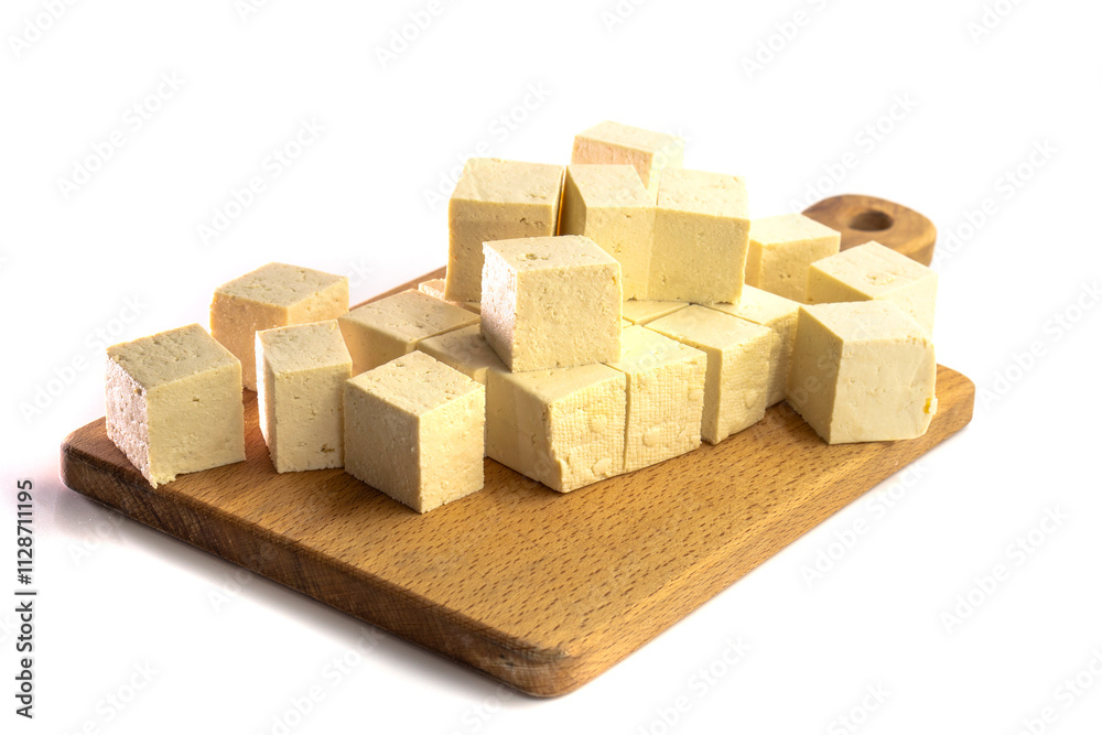 Obraz premium Pieces of raw tofu on a wooden board with soy beans.Vegan food ingredient in Asian cuisine, Plant based diet. food concept.