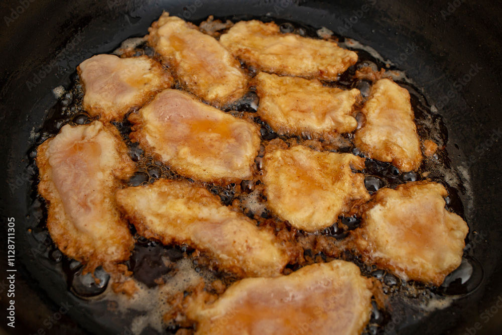 Chicken breast meat fillets with egg in boiling oil in a pan, flat lay close up Chicken breast meat fillets with egg in boiling oil in a pan, flat lay close up