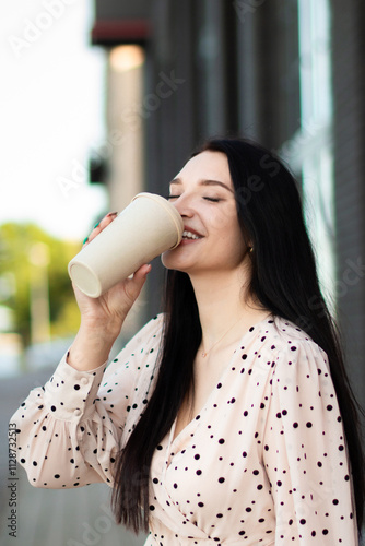 A young woman enjoys a coffee on the street on a summer's day. Lifestyle in the city. A moment of relaxation.