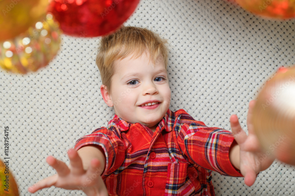 Happy Child in Festive Plaid Shirt Reaching for Christmas Ornaments Happy Child in Festive Plaid Shirt Reaching for Christmas Ornaments