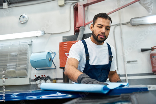 Wallpaper Mural Young mechanic carefully prepares a vehicle surface for maintenance in a bright workshop space. Torontodigital.ca