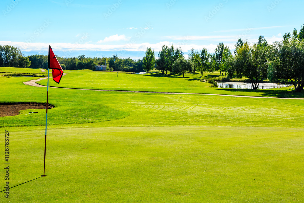Obraz premium A golf course with a red flag on the green grass