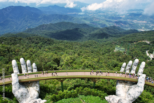 A statue depicting hands supporting a bridge over a lush forest Vietnam Da Nang Ba Na Hills Asia