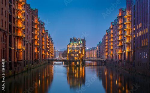 Illuminated canals reflect historic architecture at twilight in Hamburg