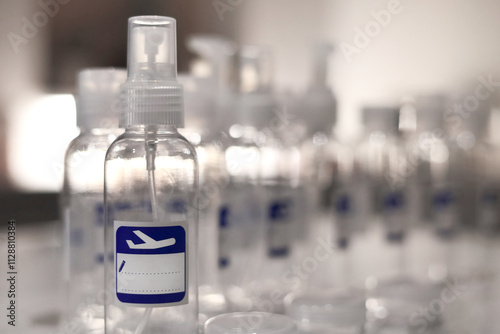 Small, transparent, plastic liquid bottles for plane traveling. Blank label with blue plane icon.