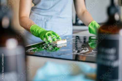 Cleaning a modern kitchen countertop with green gloves and natural cleaning products
