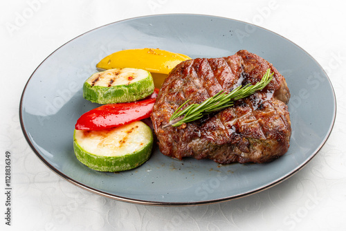 Grilled pork steak served with a colorful assortment of charred vegetables.