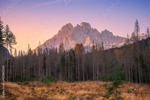 A breathtaking  dolomite mountain landscape at sunset, showcasing towering peaks and a serene forest. The golden light casts a warm glow, creating a peaceful and inspiring natural scene.