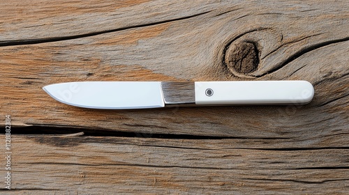 A straight razor blade on a textured wooden surface photo