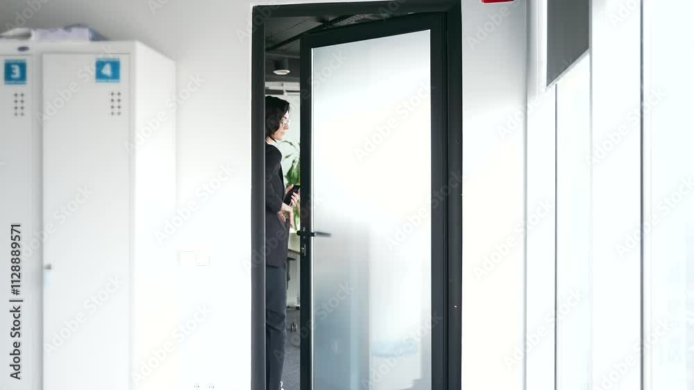 Back view of businesswoman entering modern office room through glass door. Worker making entrance. Concept of professional woman in corporate environment, workplace dynamics, and office life Back view of businesswoman entering modern office room through glass door. Worker making entrance. Concept of professional woman in corporate environment, workplace dynamics, and office life
