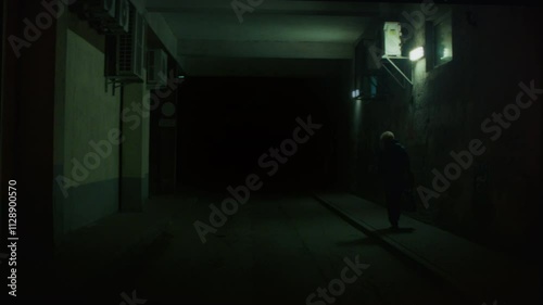 Dark creepy entrance, a parking tunnel at night with few poor lightning by dim fluorescent lamps. Woman figure walking by, on sidewalk. Green. Horror, scary, disturbing cinematic scene. Handheld. 