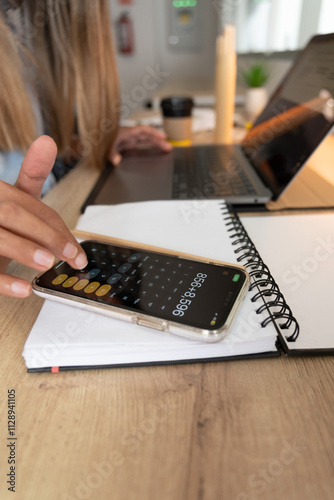 A woman is using a calculator on her phone. remote work concept