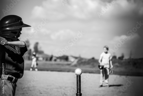 Photography Youth batter hitting a tee ball into an open field at game