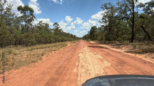 4K video, driving along red dirt outback country road, Queensland Australia, empty open landscape terrain , bushland trees blue sky