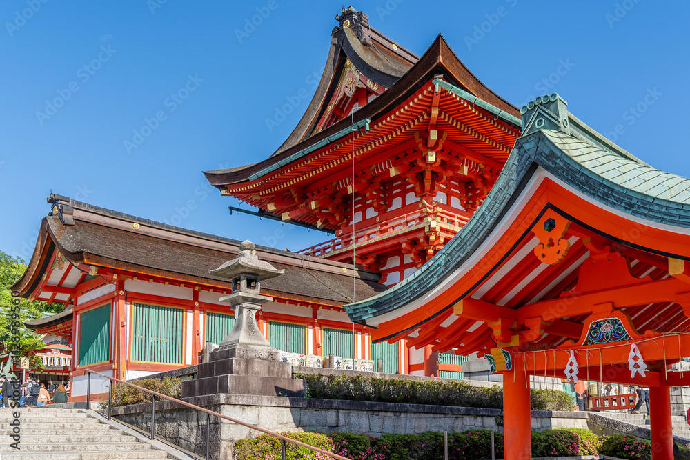 The red traditional Japanese buildings stand out beautifully against the blue sky on the grounds of the Fushimi Inari Shinto Shrine and the sacred grove of Mount Inari in Kyoto, Japan The red traditional Japanese buildings stand out beautifully against the blue sky on the grounds of the Fushimi Inari Shinto Shrine and the sacred grove of Mount Inari in Kyoto, Japan