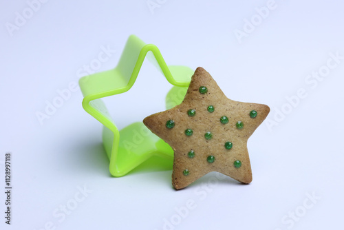 Green star shaped cookie cutter and gingerbread cookie on white background. christmas concept