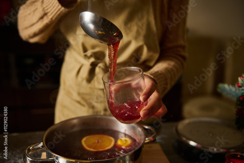 Person Serving Warm Mulled Wine from Pot into a Glass Cup