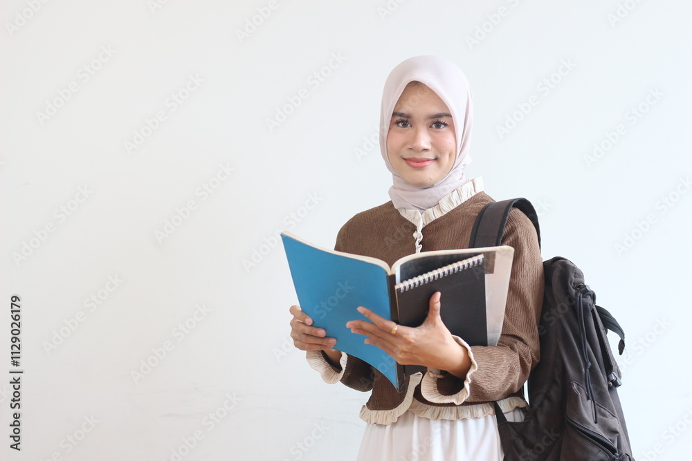 A Smiling Muslim Female Student Holding Books and Backpack Against White Background A Smiling Muslim Female Student Holding Books and Backpack Against White Background