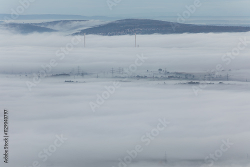 Stromleitung ragen aus dem Nebelmeer heraus. Altbacher Schornsteine im Nebel. 