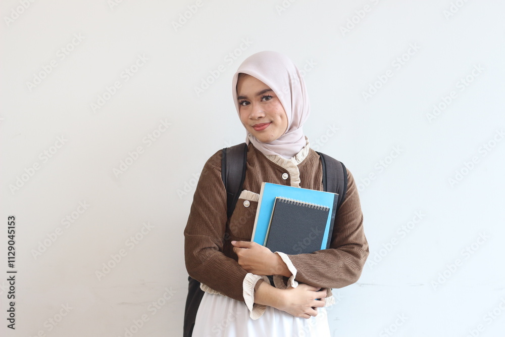 Portrait of a Smiling Muslim Female Student Holding Books Against White Background Portrait of a Smiling Muslim Female Student Holding Books Against White Background