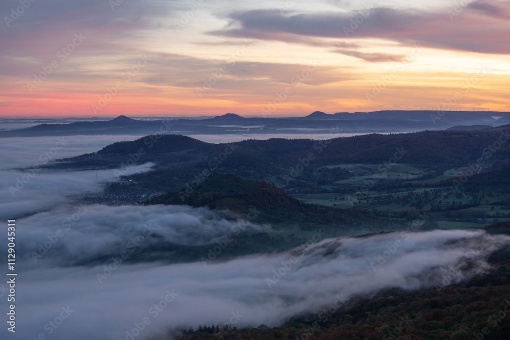 Fototapeta premium Morgenröte mit Nebel im Tal. Ausblick vom Breitenstein ( Ochsenwang ) Schwäbische Alb, Landkreis Esslingen. Am Horizont die drei Kaiserberge - Hohenstaufen, Stuifen und Rechberg. 