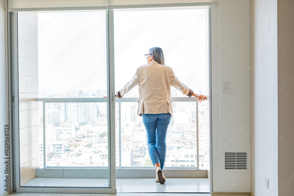 A woman stands on a balcony looking out at the city. New home concept. A woman stands on a balcony looking out at the city. New home concept.