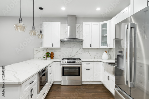 A white kitchen detail with white marble countertop and backsplash, stainless steel appliances, black pendant lights, and hardwood flooring. No brands or labels.