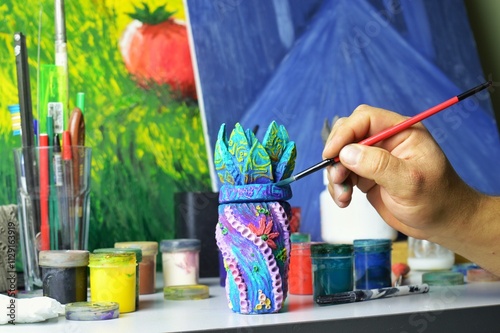 decorating a ceramic mug vessel with the hands of a master at a work table. photo without a face. the workspace of the master of pottery and ceramics is modern art and handmade art workshop. High photo