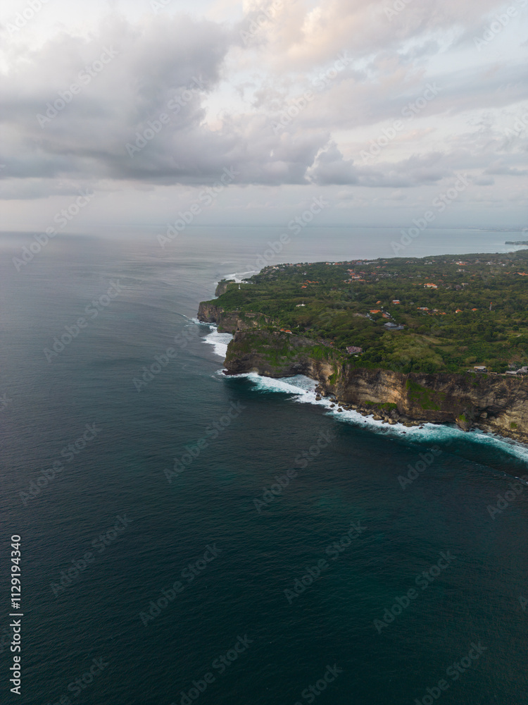 Aerial view of a coastal cliff with lush greenery and expansive ocean. Aerial view of a coastal cliff with lush greenery and expansive ocean.