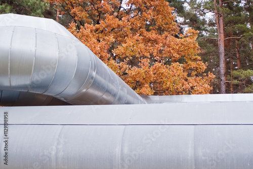 The photo shows a pipeline against the backdrop of a green forest and gray sky photo