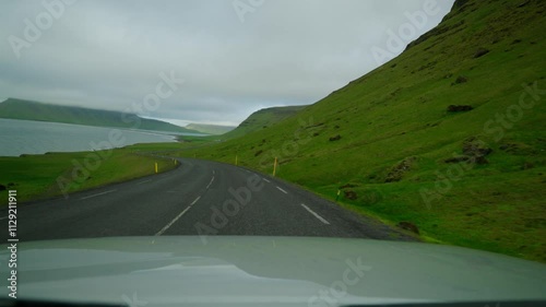 Car drives along asphalt road stretching at foot of mountain