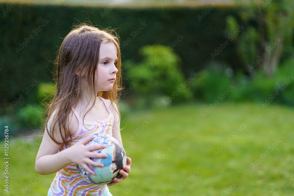 Little sad lightly dressed wet girl playing with ball in backyard in summer. Concept of cheerful active child Little sad lightly dressed wet girl playing with ball in backyard in summer. Concept of cheerful active child