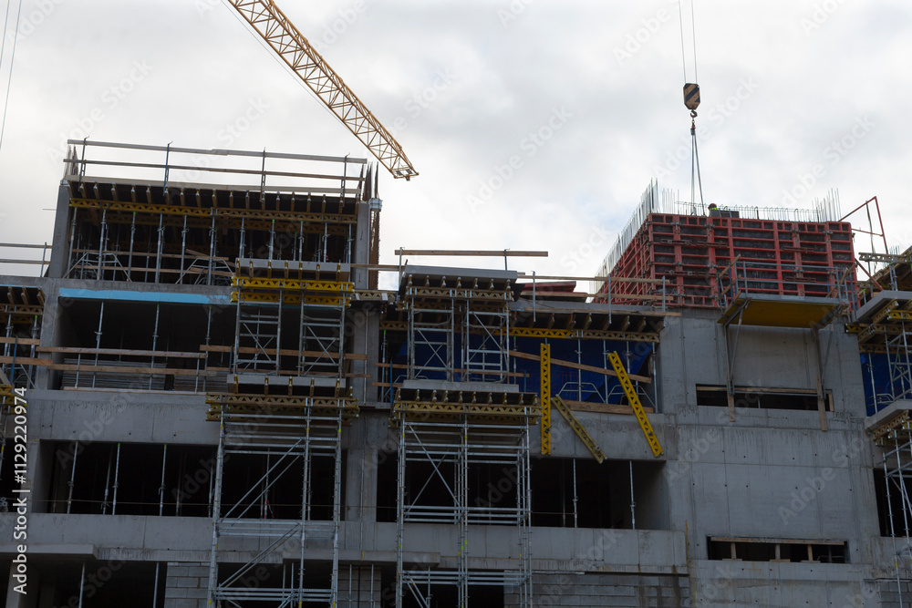 A large and impressive building is currently under construction, with a towering crane visible in the background, showcasing the progress A large and impressive building is currently under construction, with a towering crane visible in the background, showcasing the progress