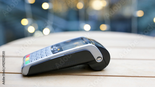 Contactless payment terminal lying on a table in a blurred background