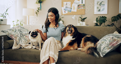 Cheerful woman, bonding and dogs with headphones, music listening and home for love as companion. Female person, technology and pet care for emotional support, happiness and streaming in living room