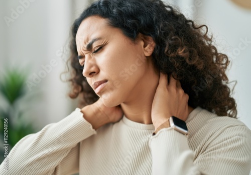 Young woman massaging her neck, suffering from chronic pain after long working day photo