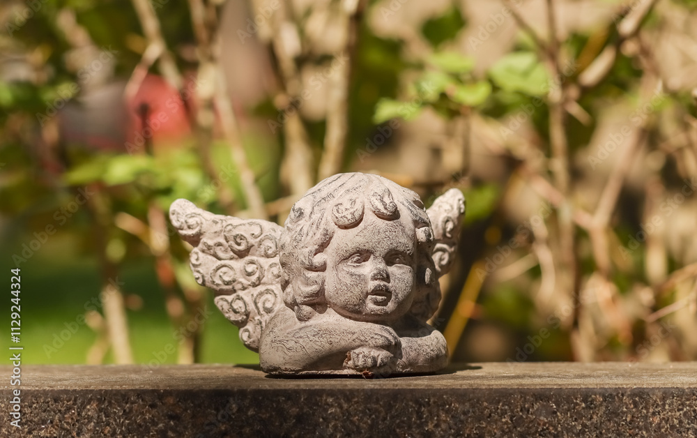 Small angel statue on a tombstone. Simple decoration angel has been brought to the graveside to comfort the grieving relatives. Empty space for text. 