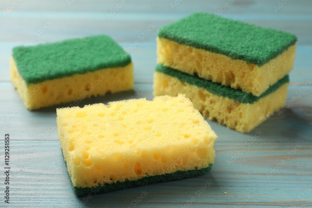 Soft sponges on light blue wooden table, closeup Soft sponges on light blue wooden table, closeup