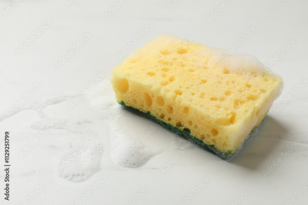 Yellow sponge with foam on white background, space for text Yellow sponge with foam on white background, space for text