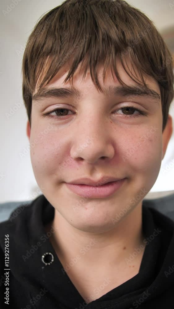 Vertical: face of cute calm caucasian teenage boy with beautiful brown eyes and calm emotions. Cute caucasian teenager smiling at camera. Attractive young teenager look straight ahead. Portrait Vertical: face of cute calm caucasian teenage boy with beautiful brown eyes and calm emotions. Cute caucasian teenager smiling at camera. Attractive young teenager look straight ahead. Portrait