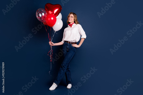 Young woman in white shirt and red scarf posing with heart-shaped balloons against a dark blue background, exuding charm and happiness