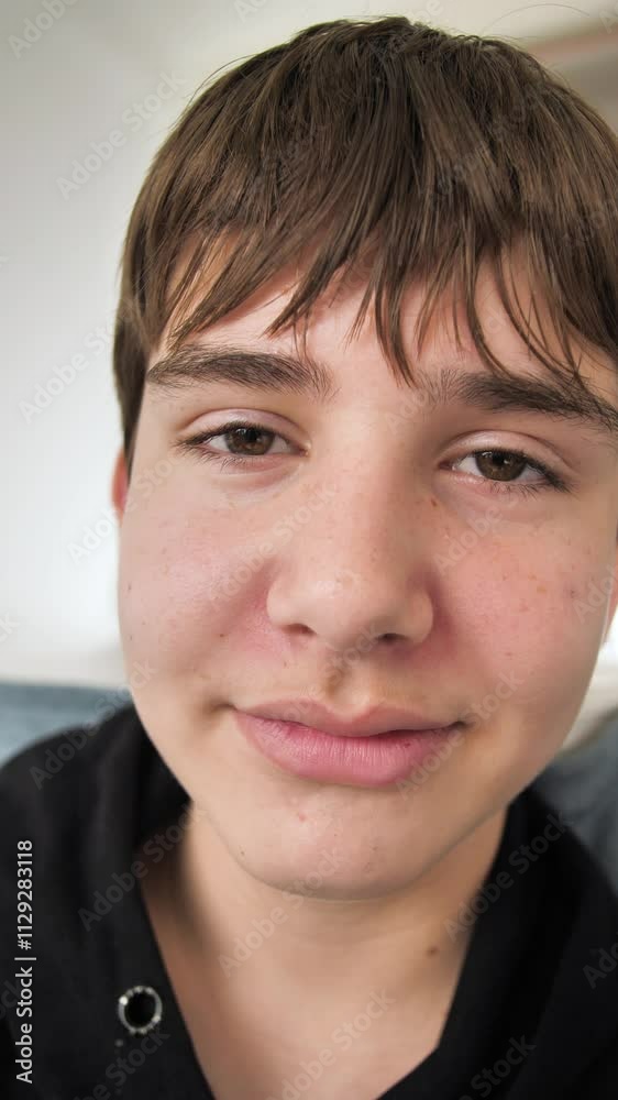 Vertical portrait of cute Caucasian teenage boy looking at camera and making grimaces. Teenager look and rolled his eyes in displeasure. Face of dark-haired boy with brown eyes and thick eyebrows Vertical portrait of cute Caucasian teenage boy looking at camera and making grimaces. Teenager look and rolled his eyes in displeasure. Face of dark-haired boy with brown eyes and thick eyebrows