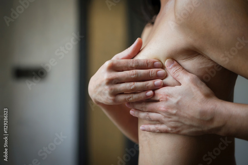 Mujer palpándose las mamas para detectar posible cáncer de mama. Generado con IA