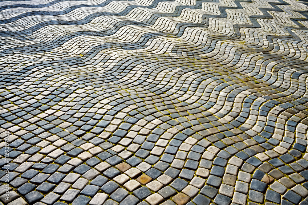 Fototapeta premium Textured cobblestone pavement with a wavy pattern showcasing various colors and shapes.