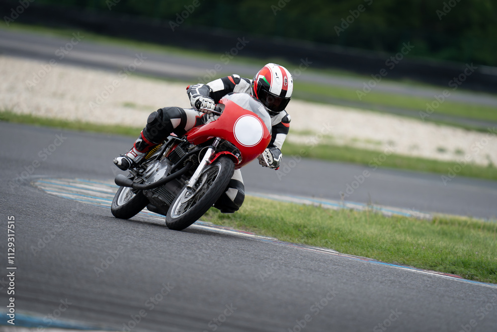 Fototapeta premium Motorcycle rider riding on a classic red sport bike through a corner.